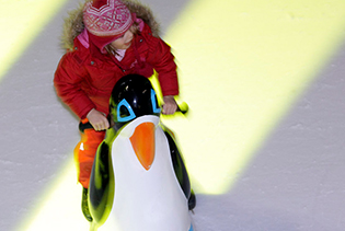 Kind mit Eislaufhilfe beim Schlittschuhlaufen